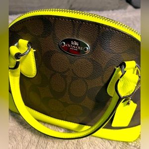 COACH “Cora” domed satchel in signature coated canvas w/ neon statement.